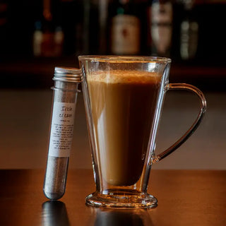 A glass mug filled with coffee next to a tube labeled 'DRINK MIX'.