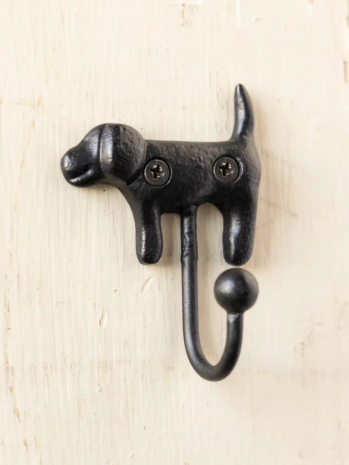 Black dog-shaped wall hook on a light wood background