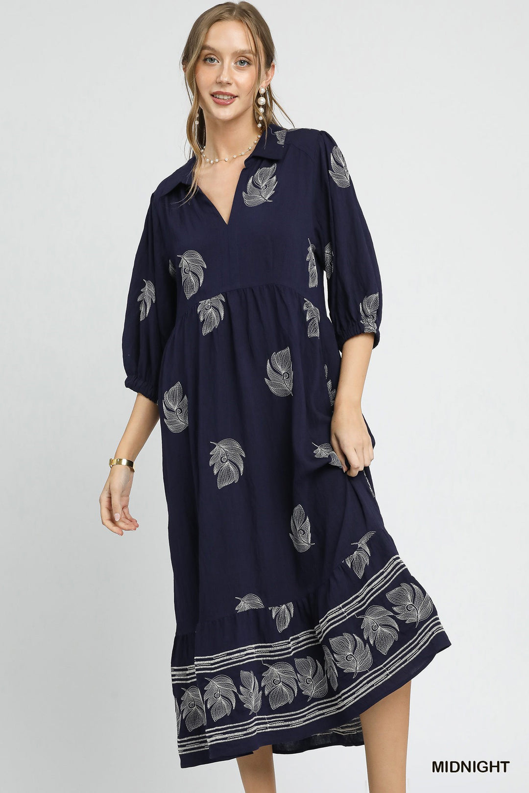 Woman wearing a navy dress with floral patterns on a light gray background