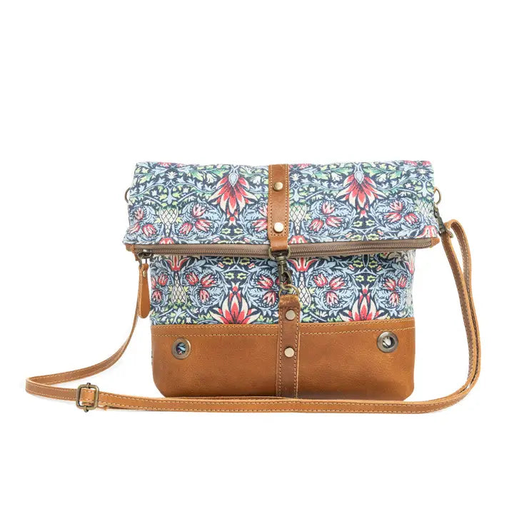 Floral-patterned handbag with brown leather accents on a white background
