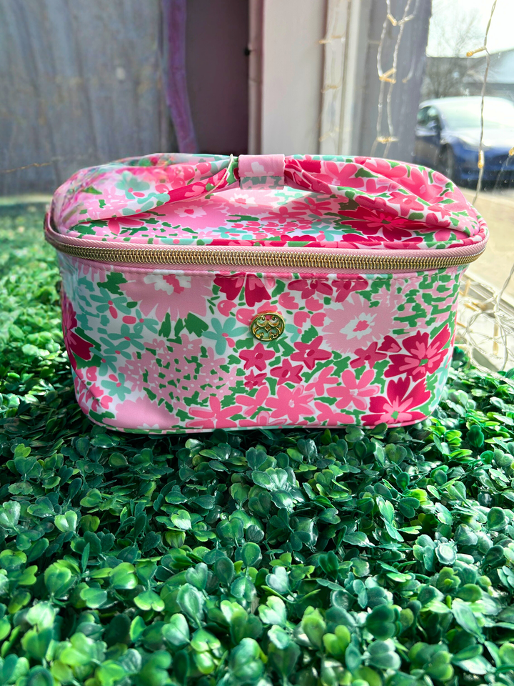 Floral-patterned cosmetic bag on a green surface