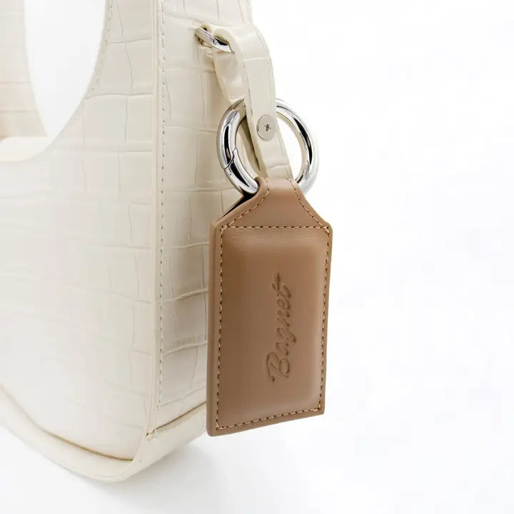 Beige handbag with a matching keychain on a white background