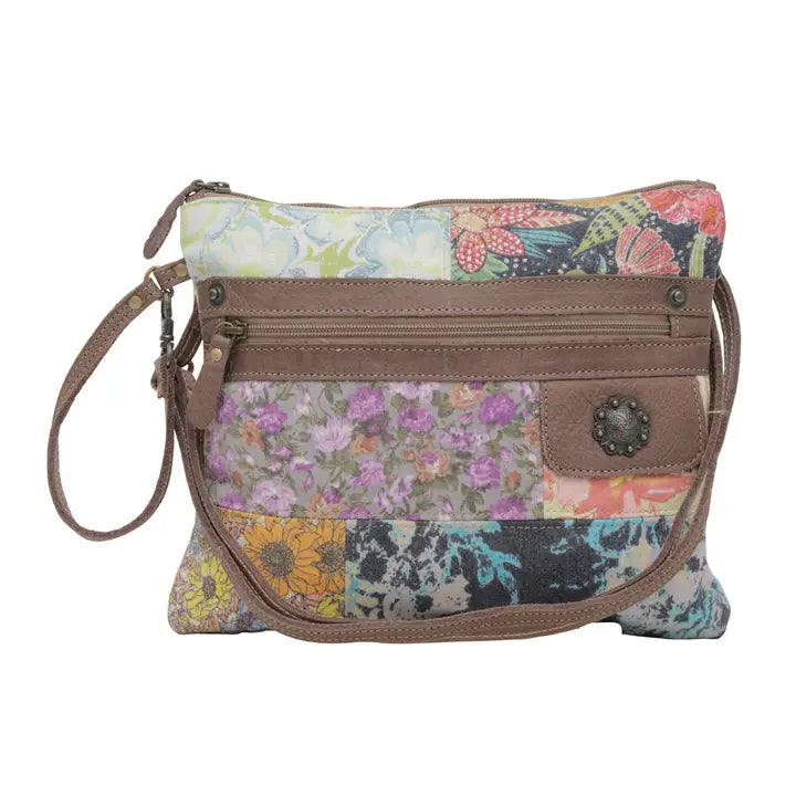 Floral patterned crossbody bag with brown leather accents on a white background