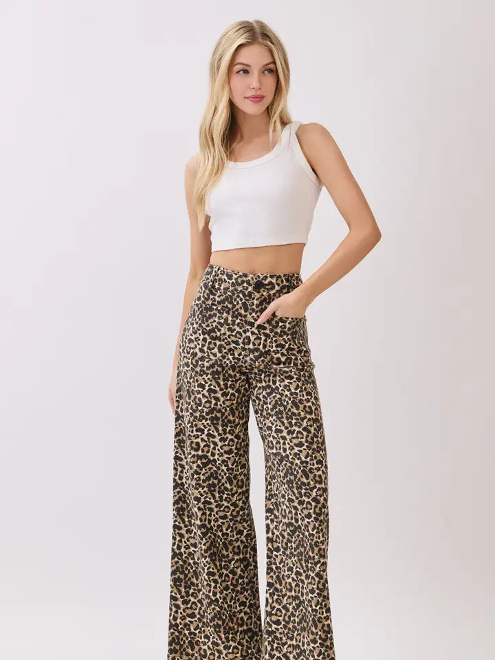 Woman wearing a white crop top and leopard print pants on a white background