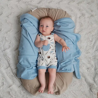 Baby lying on a cushion with a blue blanket