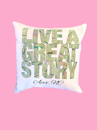 Decorative pillow with 'Live a Great Story Apex, NC' text on a pink background
