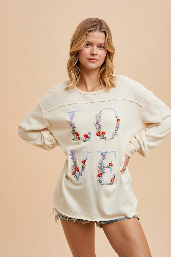 Cream colored pull over with LOVE written with blue and flowers