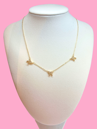 Gold necklace on a mannequin bust against a pink background