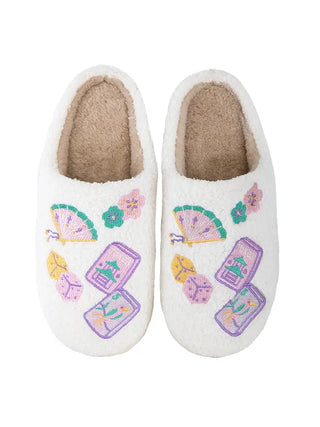 A pair of white sherpa slip-on slippers decorated with colorful embroidered Japanese-inspired motifs, including fans, flowers, and mahjong tiles, shown against a plain white background.
