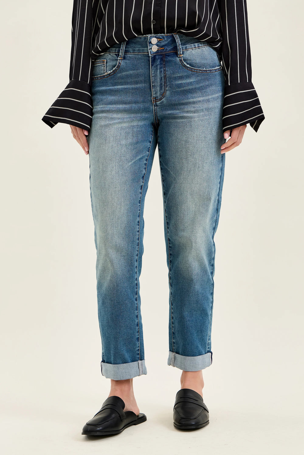 Person wearing blue jeans and a black and white striped shirt on a beige background