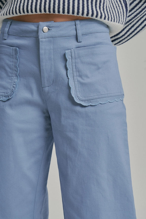 Light blue jeans with scalloped pocket edges on a gray background