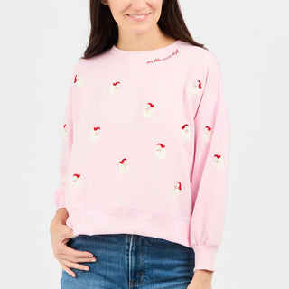woman wearing a pink sweatshirt with small santa boucle appliques and embroidery near the collar "on the nice list"