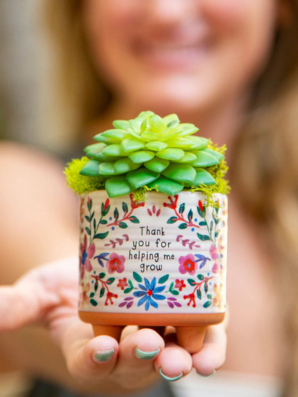 Small potted succulent with a decorative pot featuring floral designs and text.