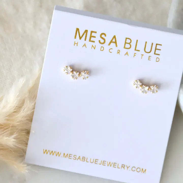 Gold earrings on a Mesa Blue jewelry card with a white background
