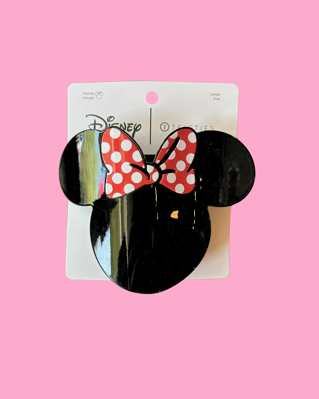 Black mouse ears with a red polka dot bow on a pink background