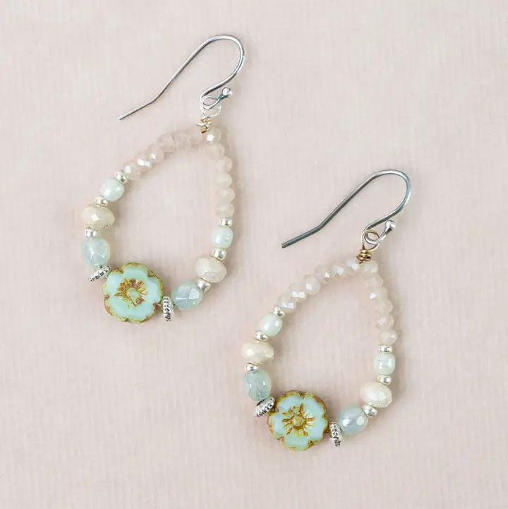 Pair of beaded earrings with floral designs on a pink background