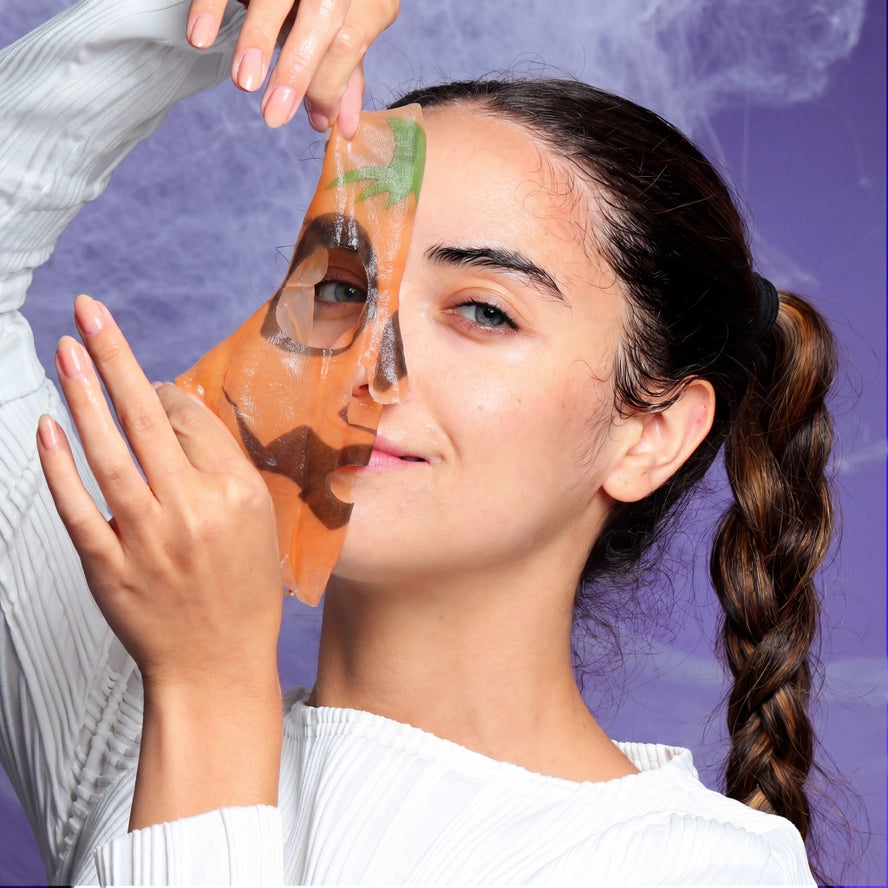 girl putting on a pumpkin character face mask