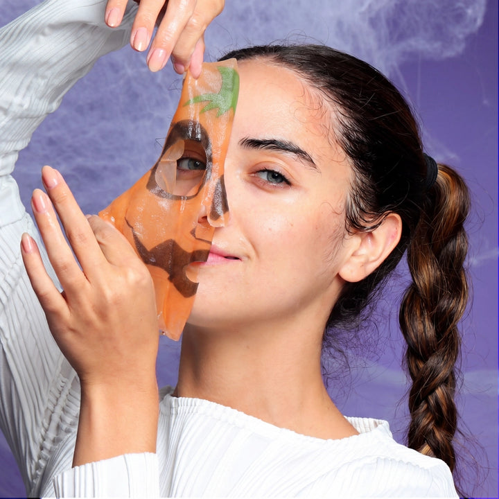 girl putting on a pumpkin character face mask