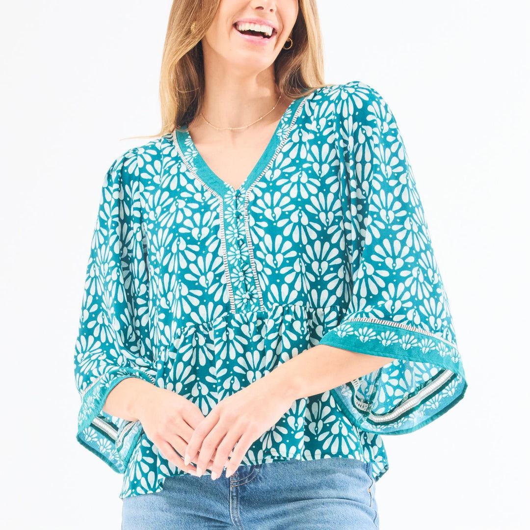 Woman wearing a turquoise floral blouse with a plain background