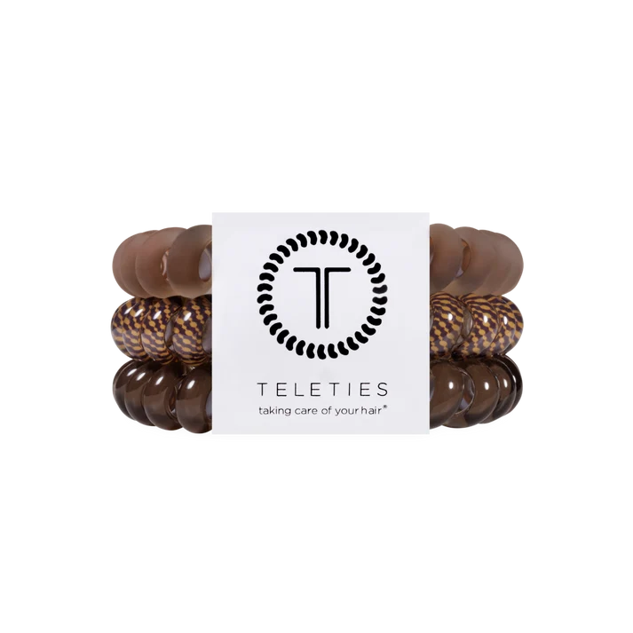 A set of four Teleties hair stretch bands in shades of brown, including solid medium brown, dark brown, and tortoiseshell patterns, wrapped around a white paper band with the Teleties logo.