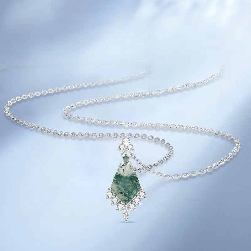 Silver necklace with a green pendant on a light blue background