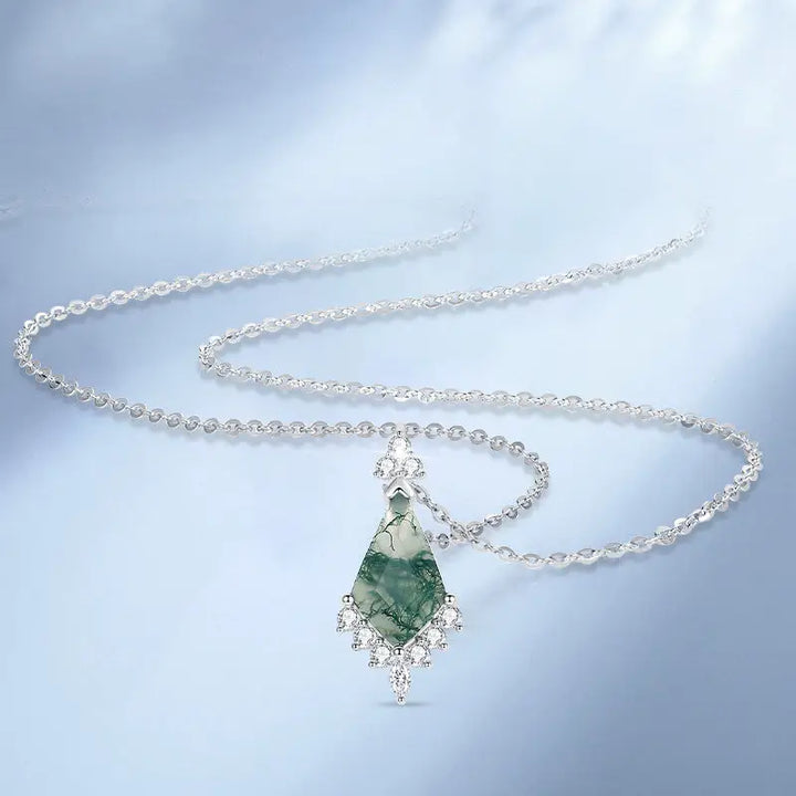 Silver necklace with a green pendant on a light blue background