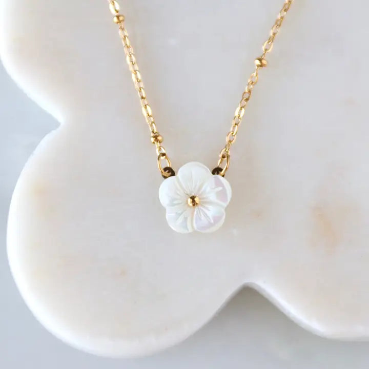 Necklace with a white floral pendant on a white dish