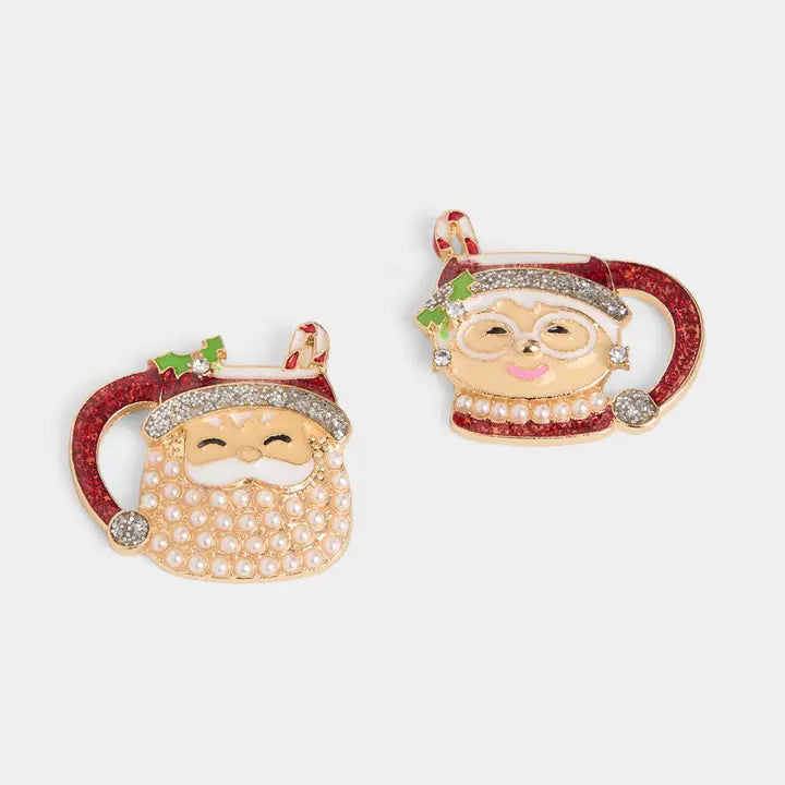 Two Christmas-themed earrings shaped like Santa Claus with a mug on a white background