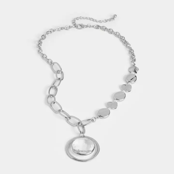Silver necklace with circular pendant on a light gray background