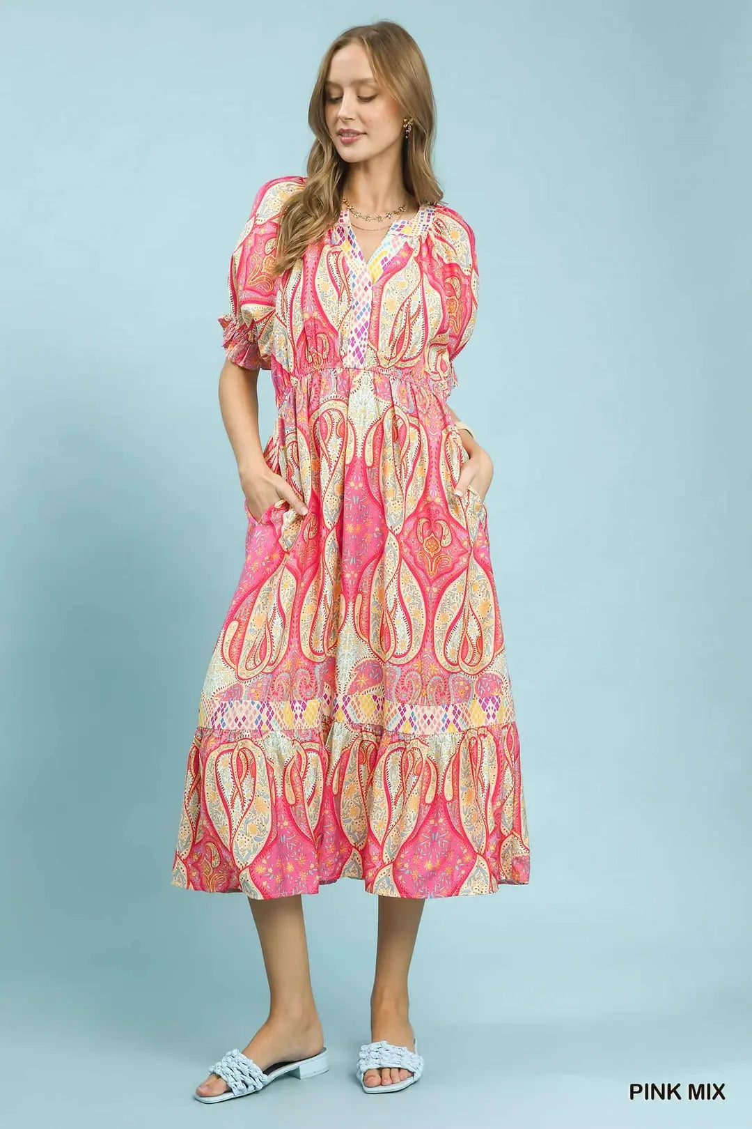 Woman wearing a pink and white patterned dress on a light blue background