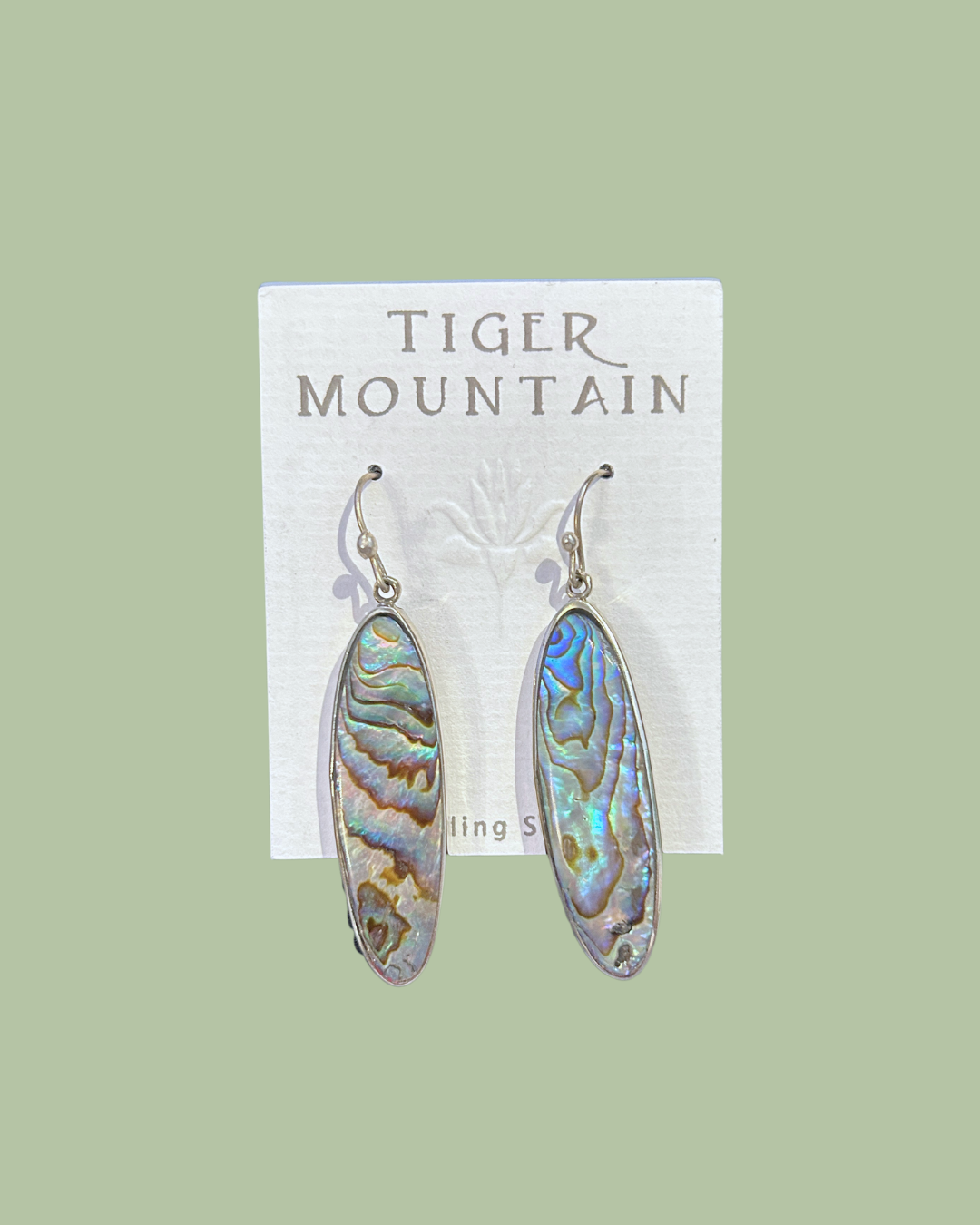 Pair of earrings on a 'Tiger Mountain' branded card against a light green background