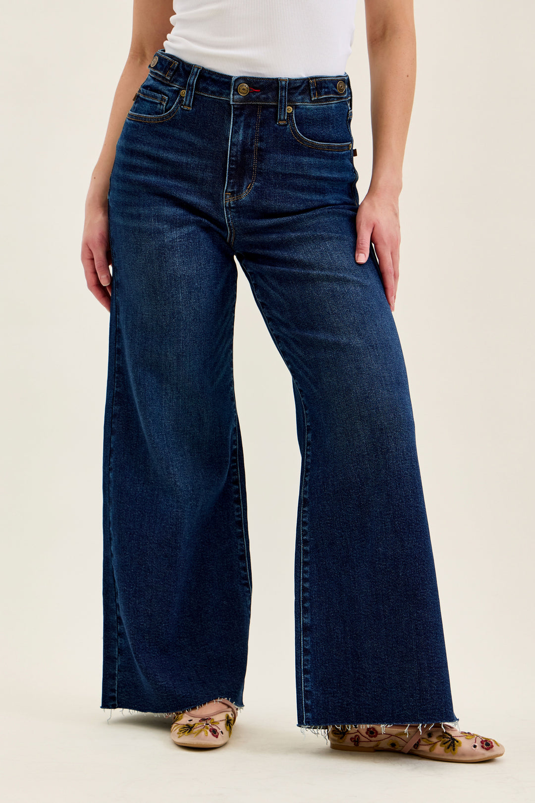 Person wearing blue wide-leg jeans on a plain background