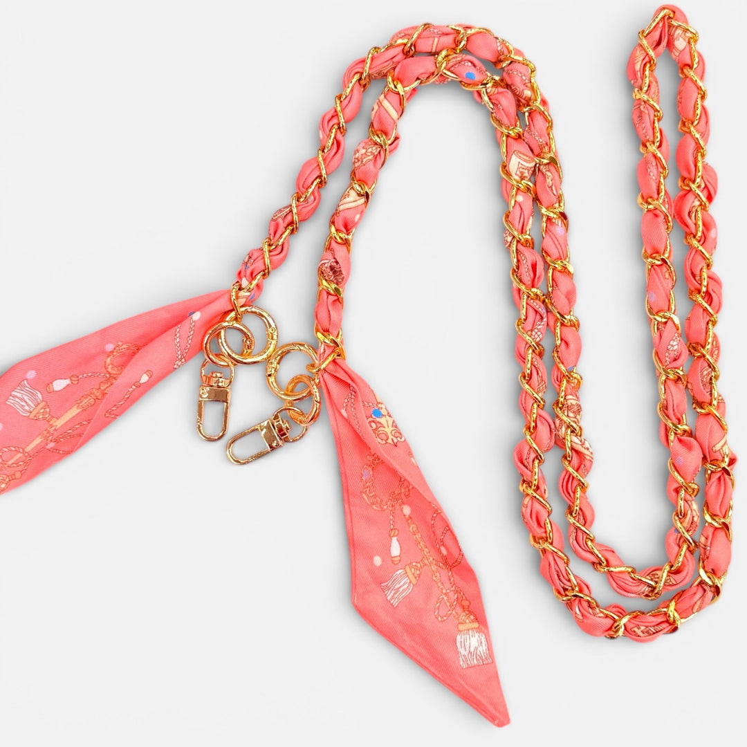 Coral-colored lanyard with gold accents and a matching fabric strap on a white background