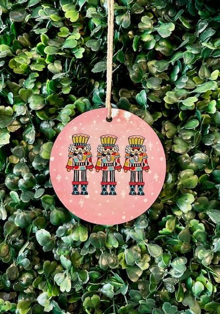 Decorative ornament with nutcrackers on a pink background hanging on a green leafy background
