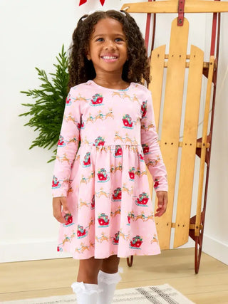 little girl wearing pink long sleeve dress with reindeer and sleigh pattern