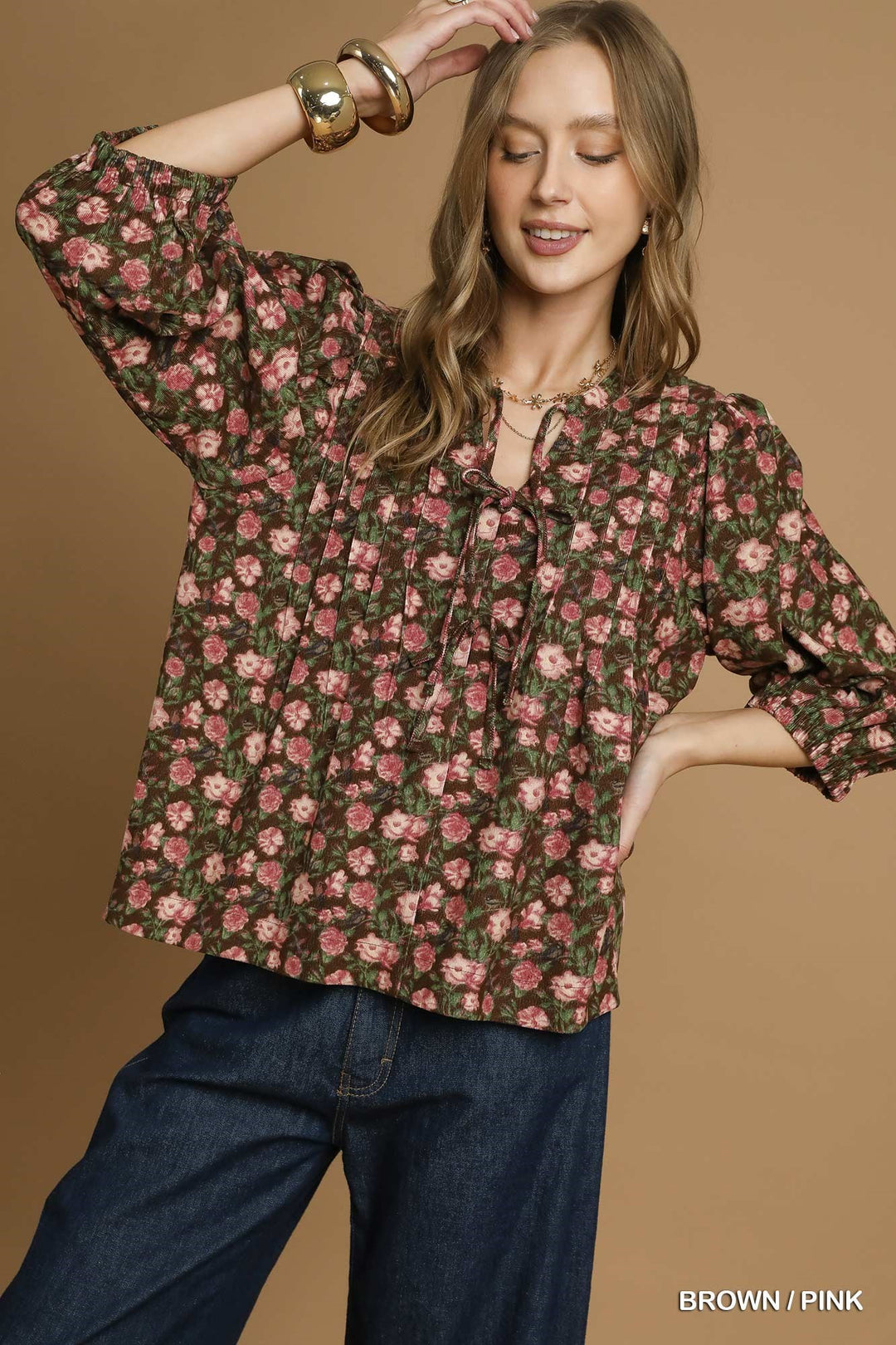 Woman wearing a floral blouse with long sleeves on a brown background