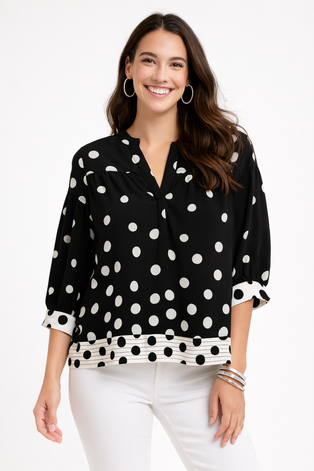 Woman wearing a black blouse with white polka dots and white pants on a white background