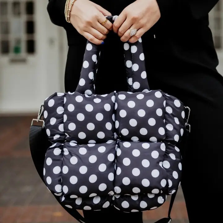 Black bag with white polka dots held by a person