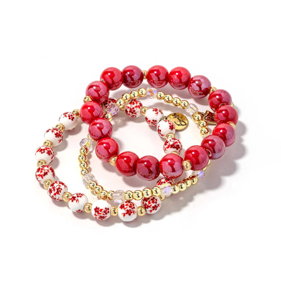 Stack of red, white, and gold beaded bracelets on a white background