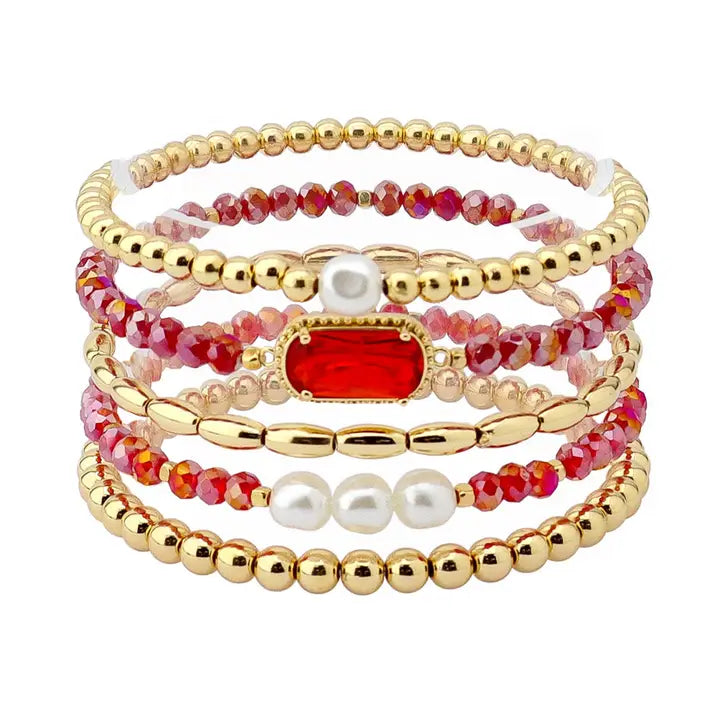 Set of beaded bracelets with gold, red, and pearl accents on a white background