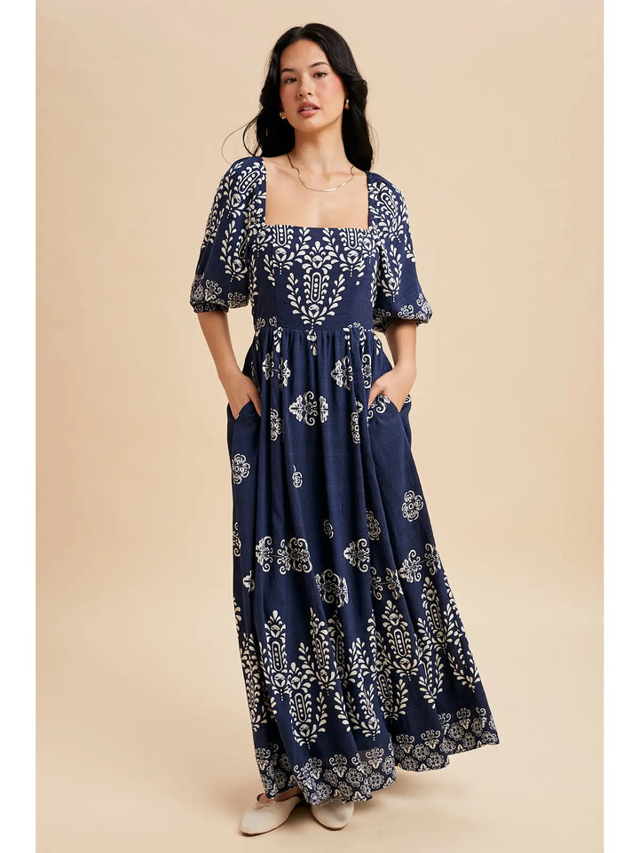 Woman wearing a navy blue floral dress against a beige background