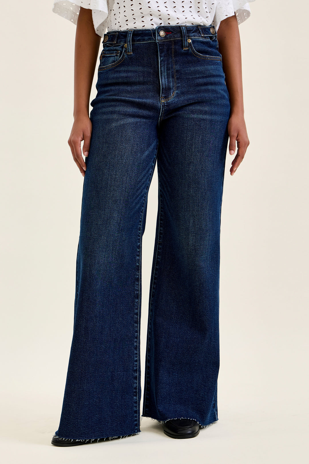 Person wearing blue flared jeans on a plain background