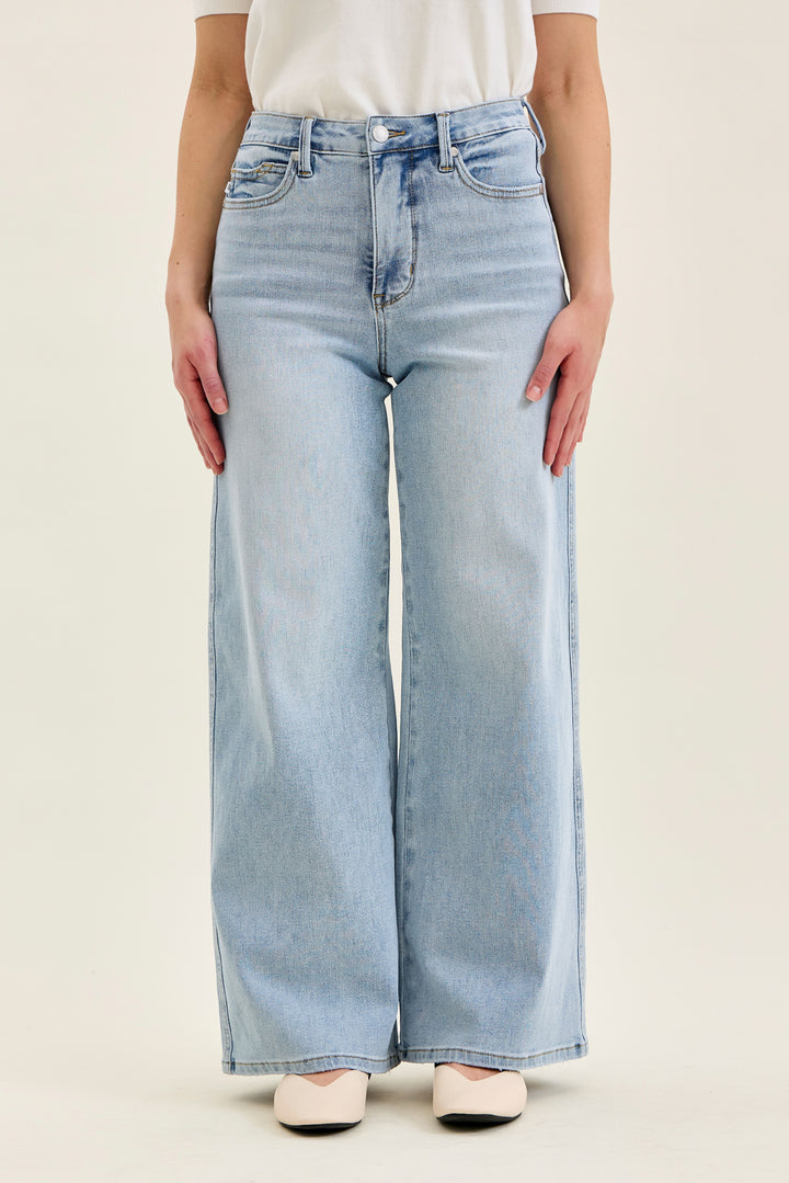 Light blue jeans worn by a person on a beige background