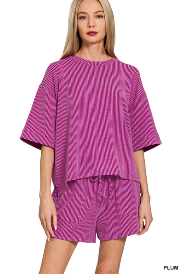 Woman wearing a purple ribbed top and shorts set on a white background