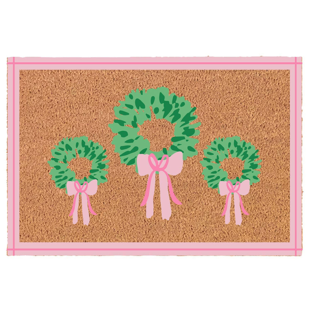 Doormat with green wreaths and pink bows on a cork background