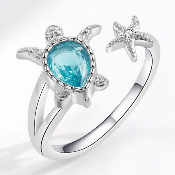 Silver turtle-shaped ring with a blue gemstone on a white background