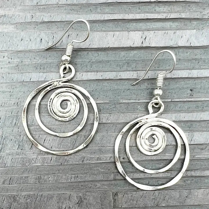 Silver spiral earrings on a wooden surface