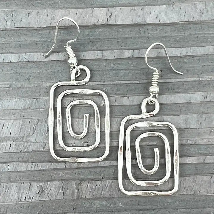 Silver spiral earrings on a wooden surface
