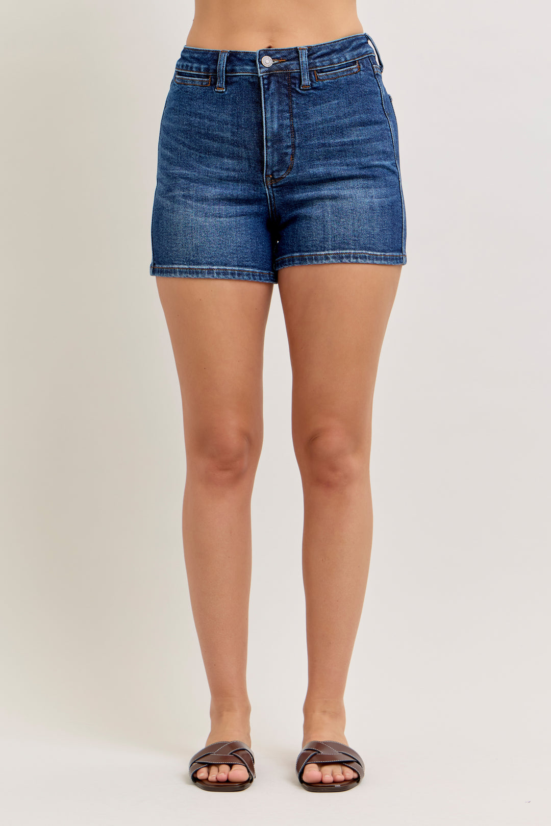 Blue denim shorts worn by a person on a plain background
