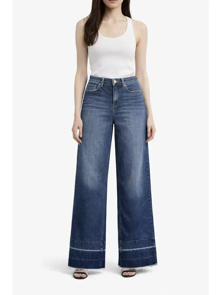 Woman wearing blue wide-leg jeans and a white tank top on a white background